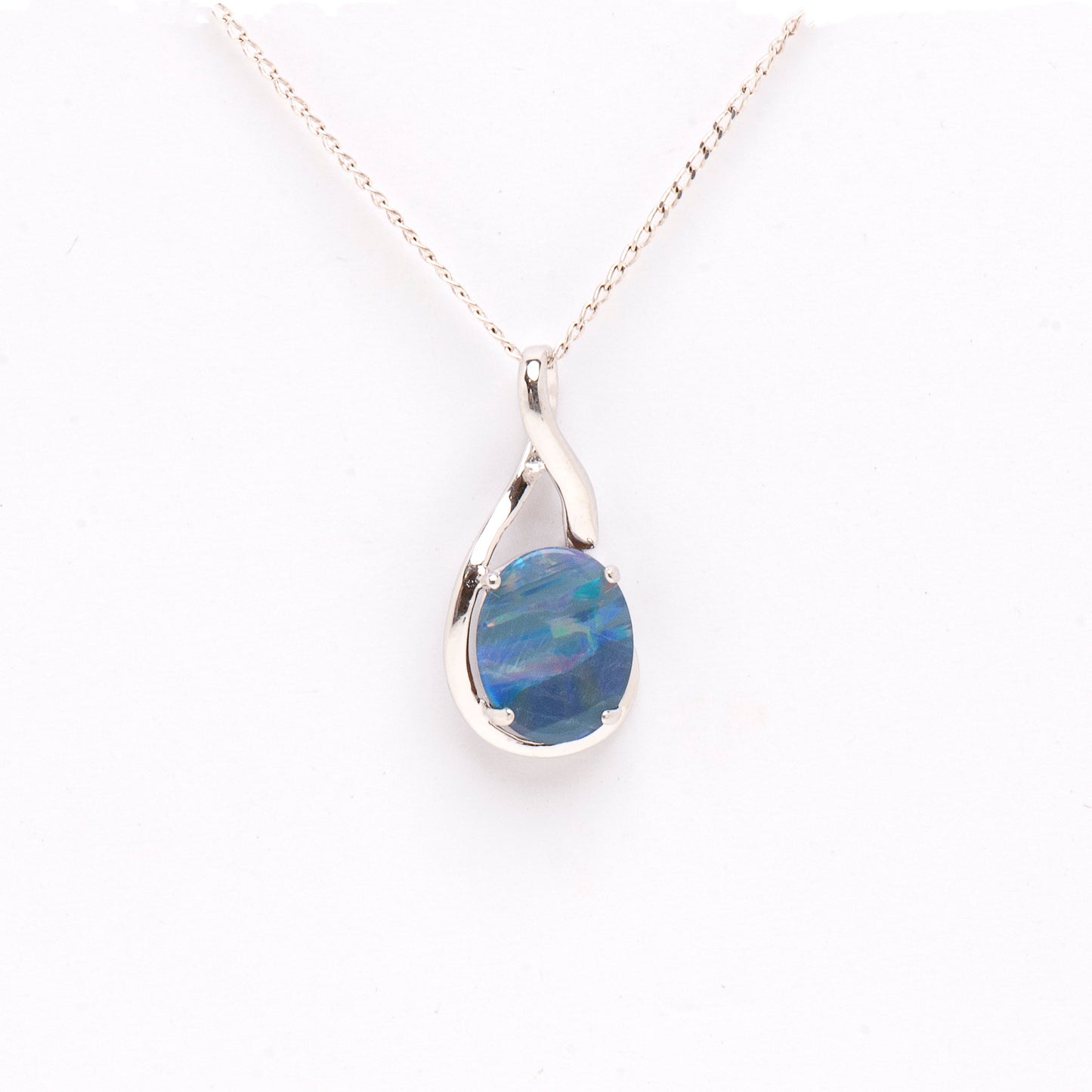 A Sterling Silver Doublet Opal Pendant featuring an oval-cut opal with a unique stripe pattern. The opal displays an array of rainbow colours against a deep blue background, set in a sleek sterling silver claw setting | Opalist