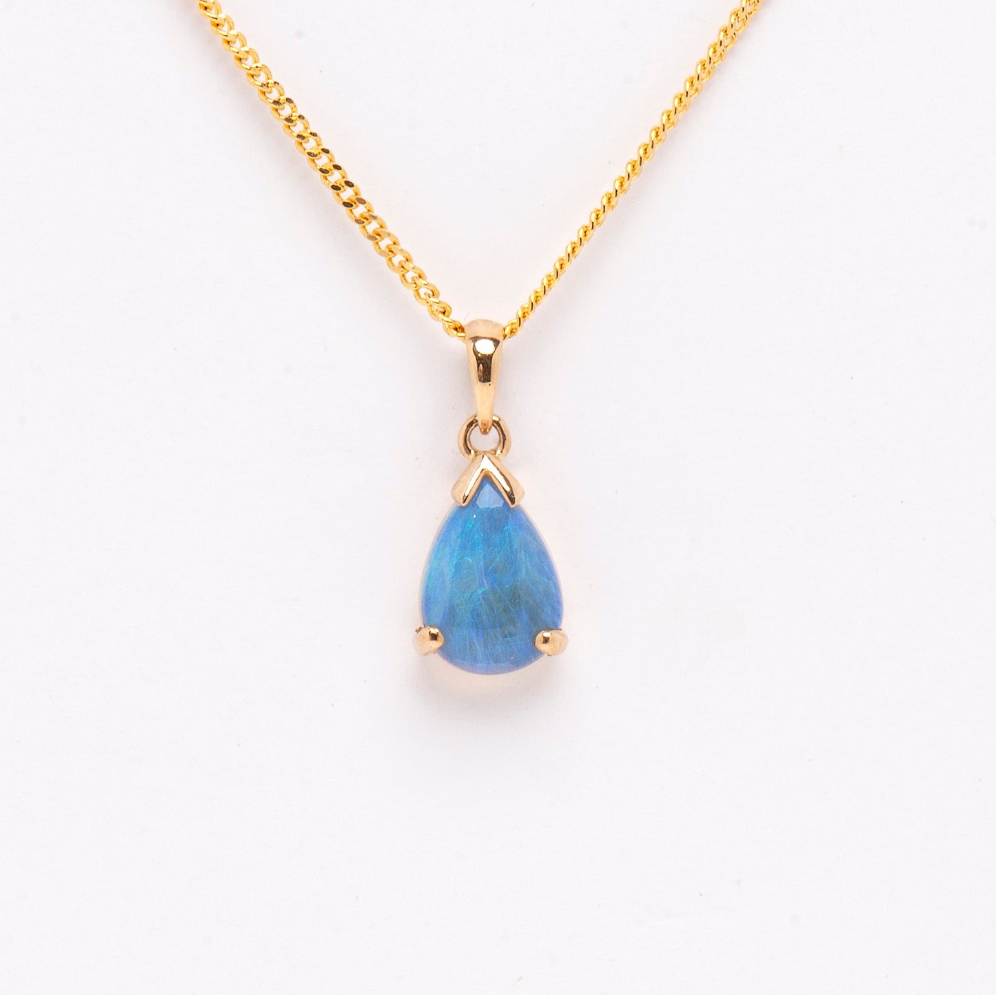 9ct Yellow Gold Enhanced Crystal Opal Pendant. The pendant features a pear-cut opal in shades of blue and green, with a 9ct yellow gold backing. The opal is claw-set, showcasing its natural beauty and color | Opalist